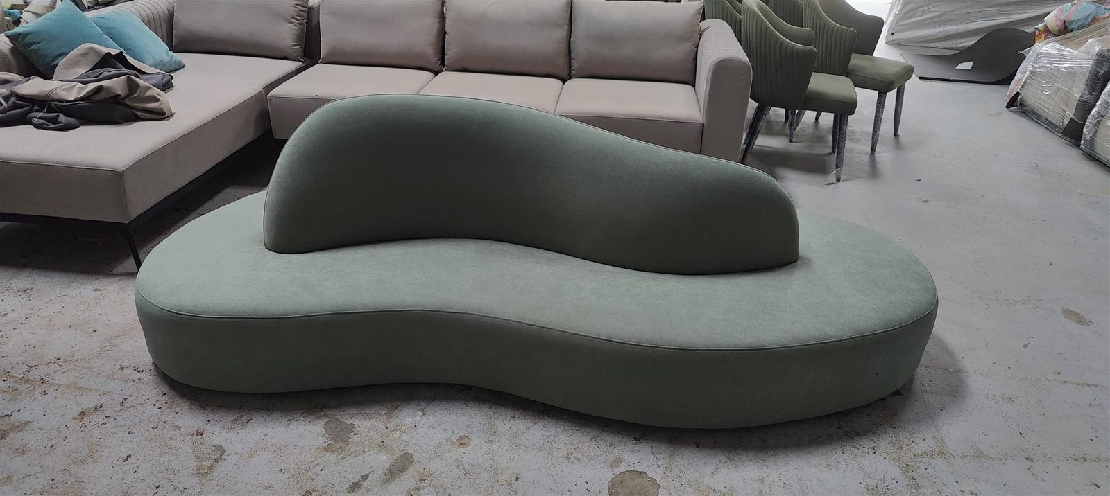 Sage green kidney-shaped curved sofa built at the KMF Living factory in Cherlapalli, Hyderabad