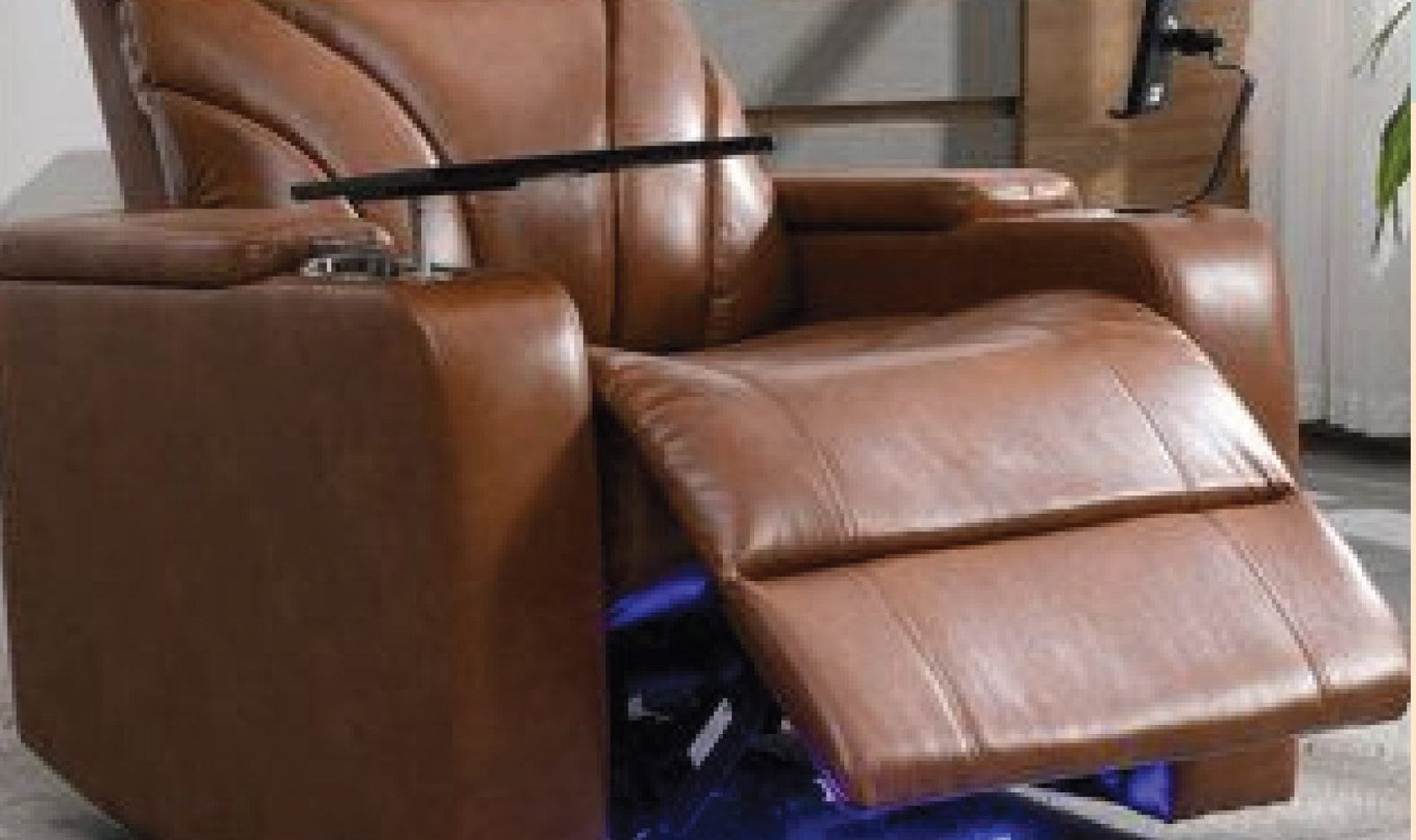 Motorised leather recliner with the footrest extended, showing the mechanism underneath